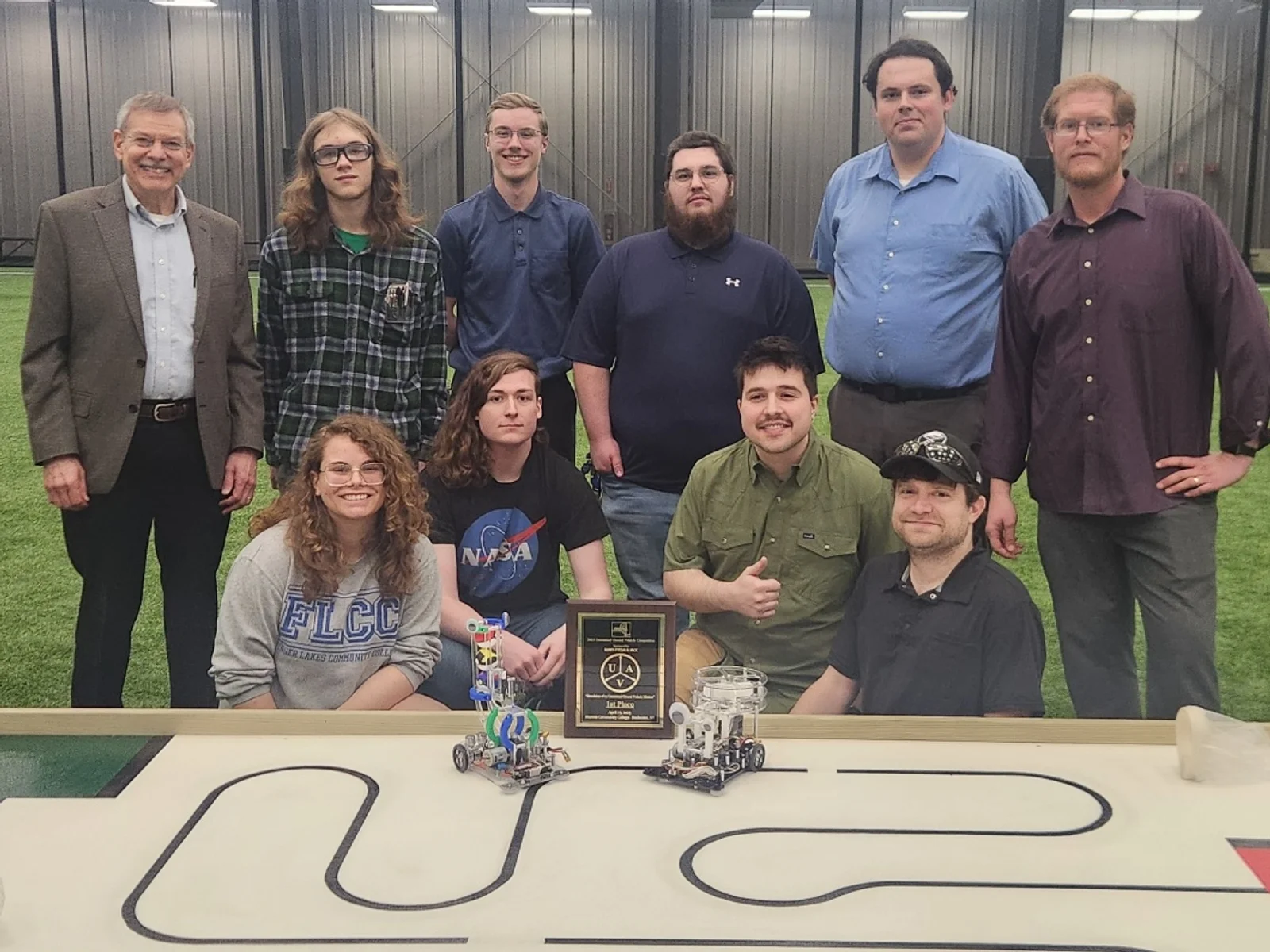 A group of eight engineering students and two advisors posing with robots they built