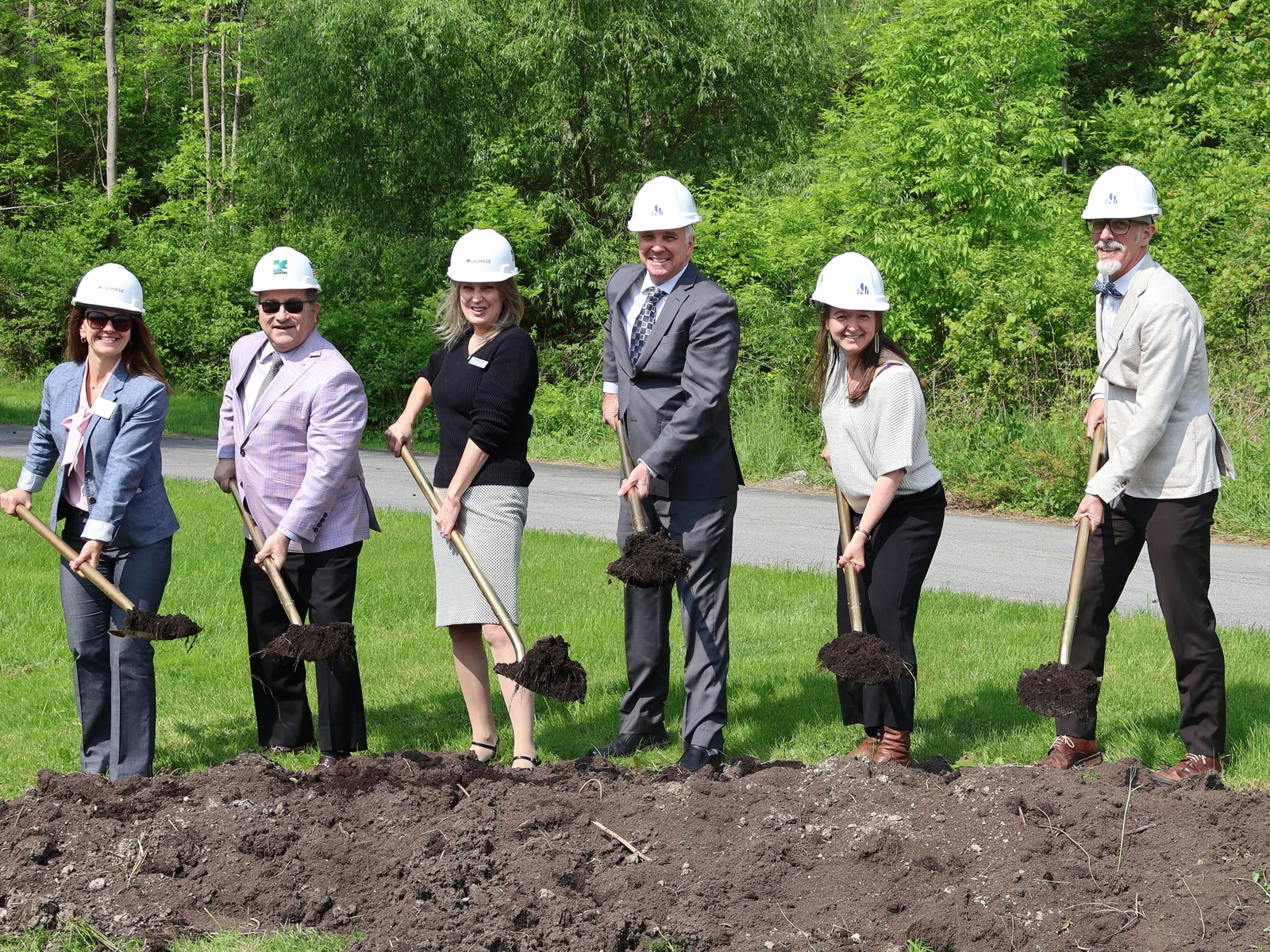 Six individuals holding gold ceremonial shovels for a groundbreaking event.