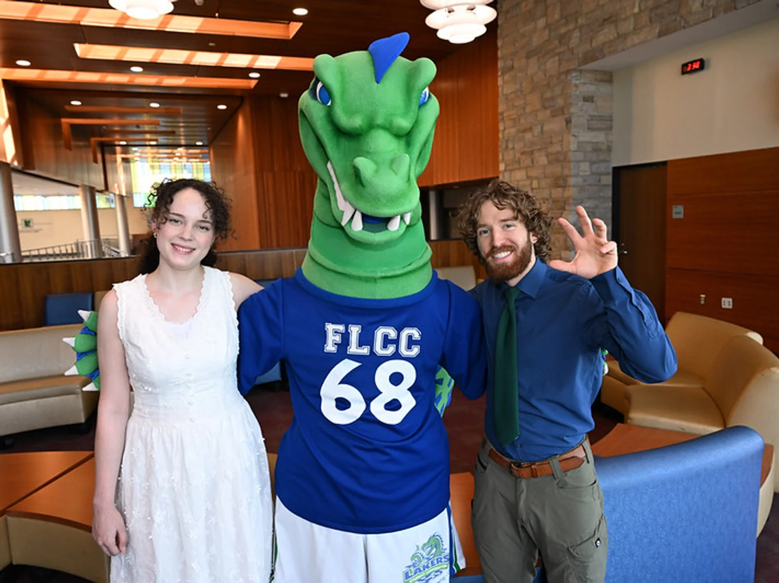 A young man and woman posing on either side of the FLCC mascot