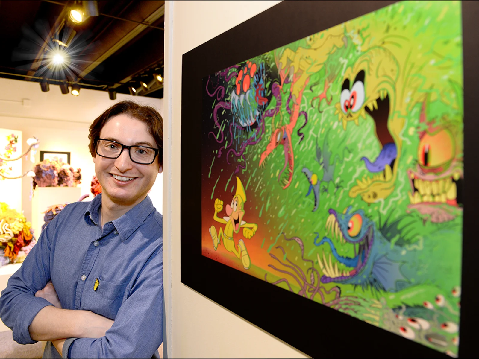 Ryan Kovar '12, poses with one of his illustrations. Photo by Rikki Van Camp