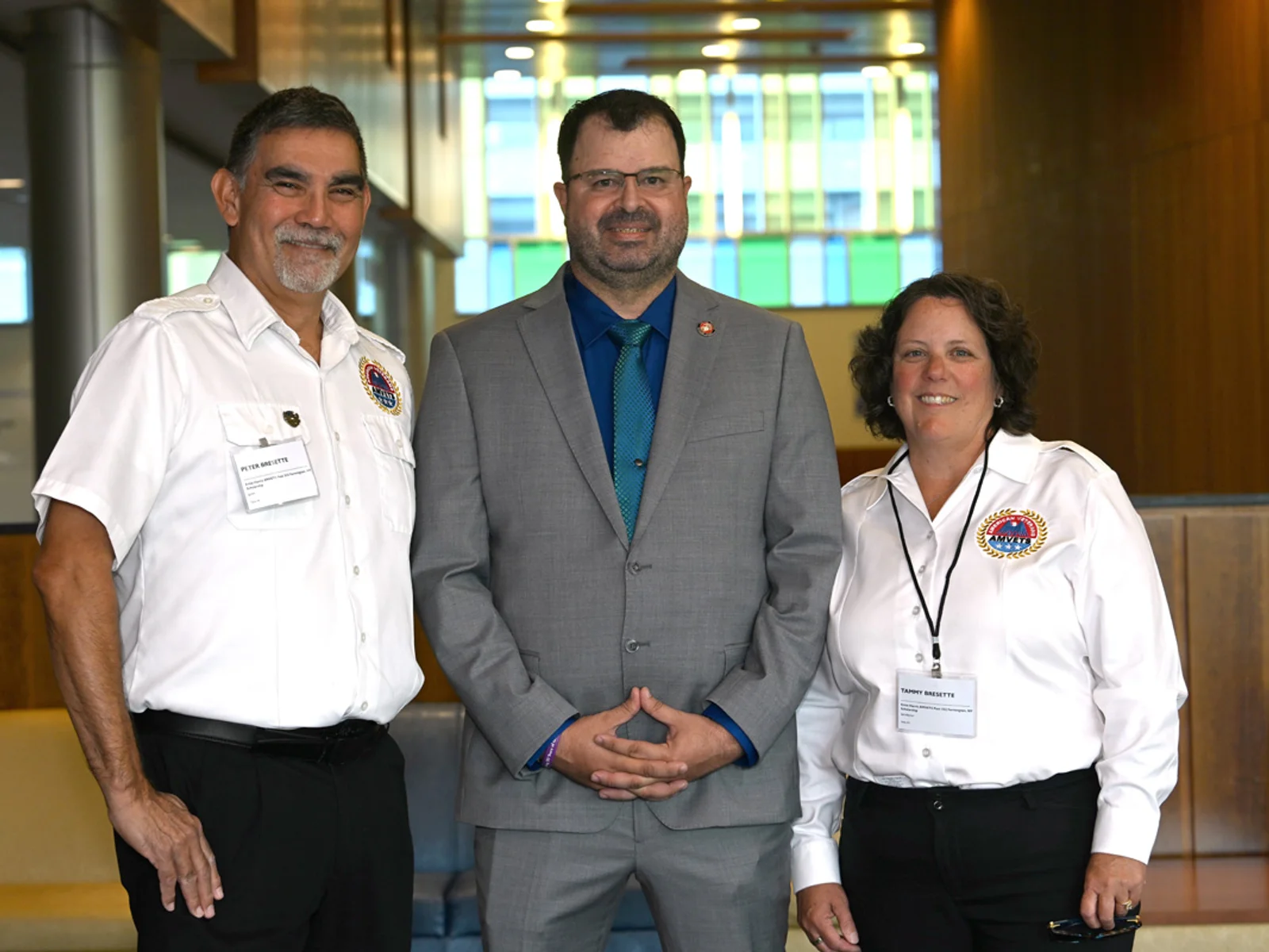 A man in a suit posing between an man and woman in white shirts