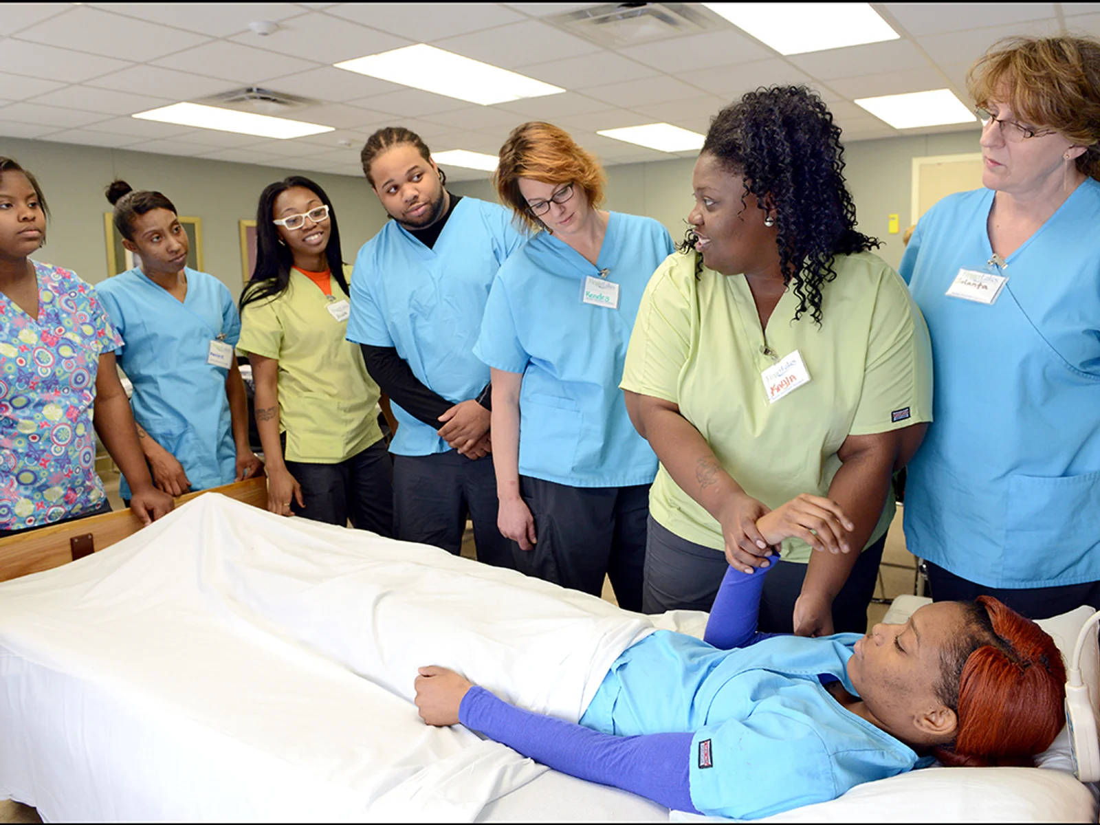 Nurse assistant students watching demonstration at patient bed