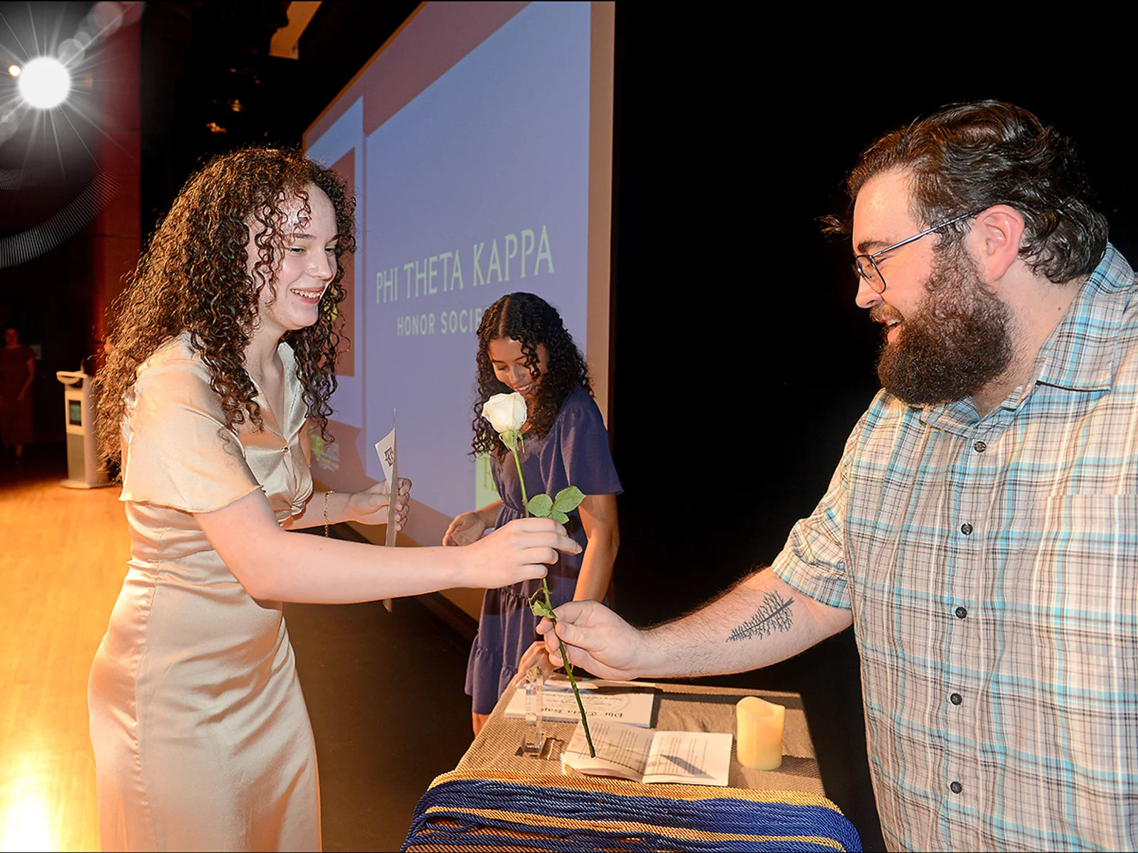 Man handing white flower to a woman at a ceremony