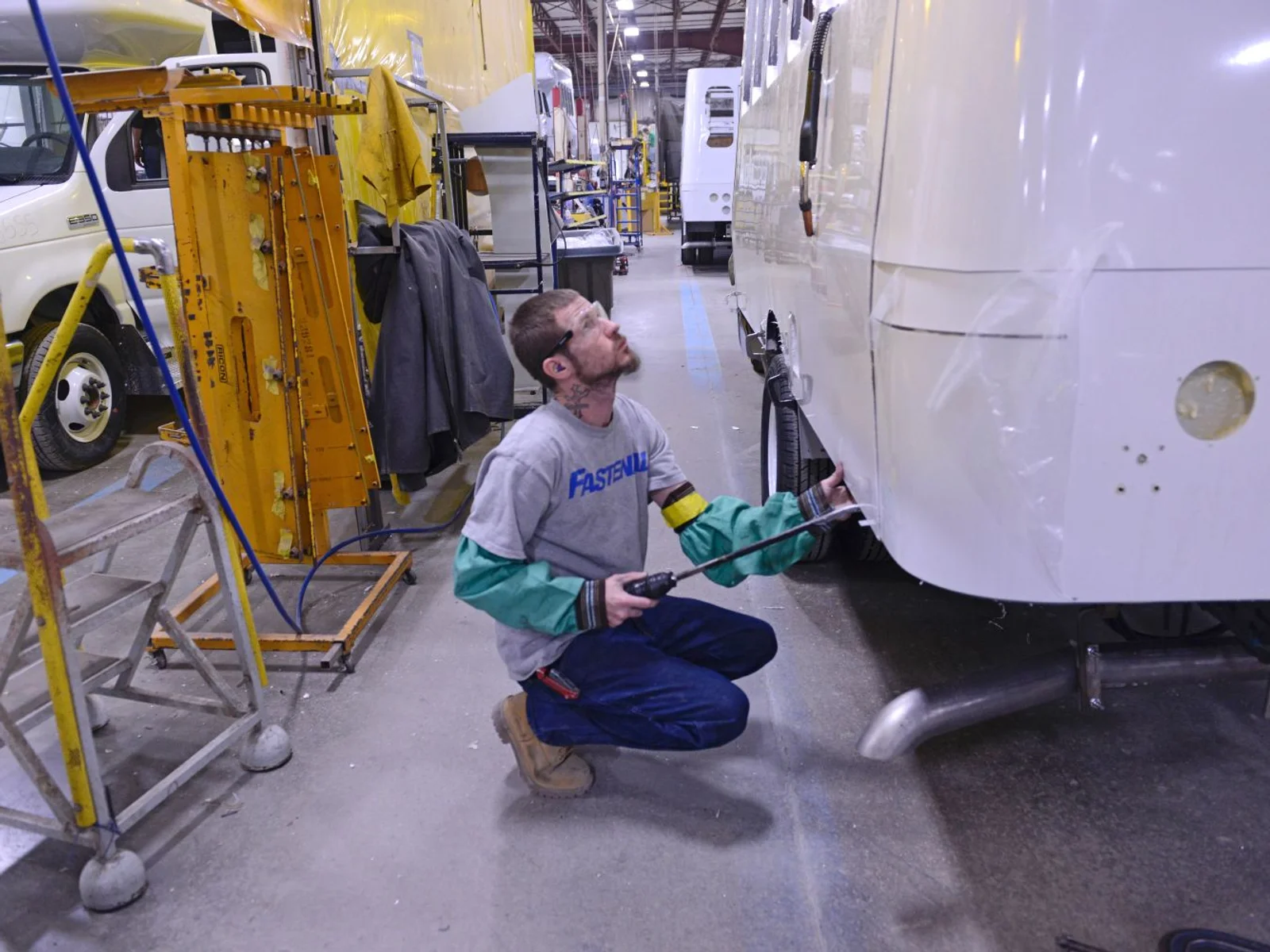 An instructor stands next to a man in a welding helmet using computer simulation technology