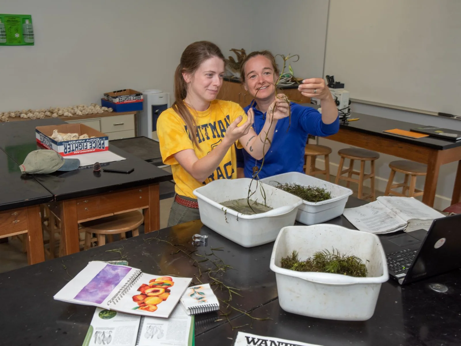 Two women examining tubs of aquatic plants
