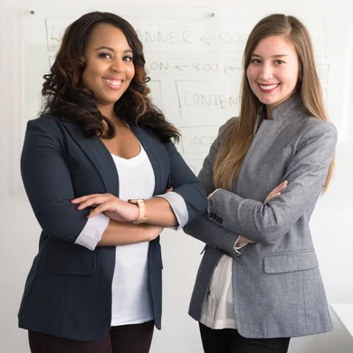 Two employees in a business setting with marketing charts and graphs displayed on the walls.