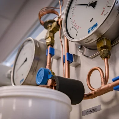 Close-up view of the analog pressure gauges of the refrigeration demonstration unit.