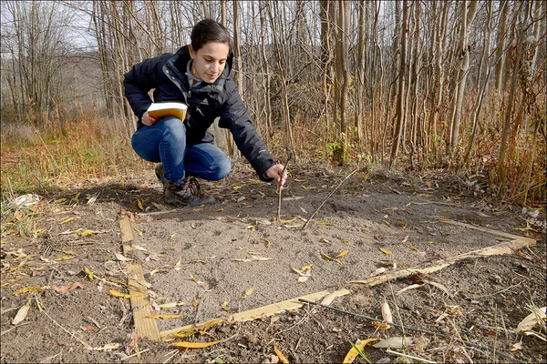 Woman bending over a shallow sandbox