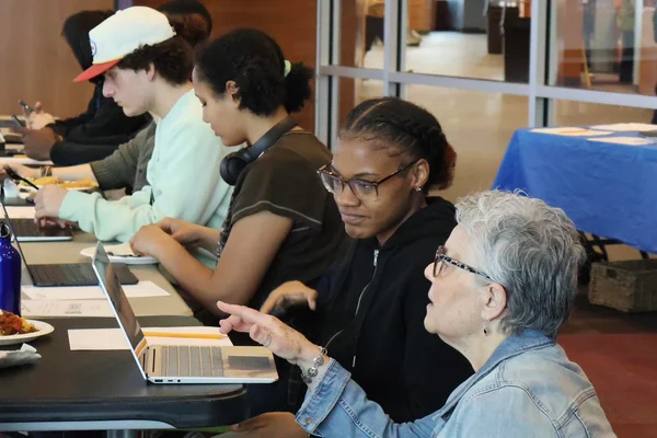 A woman helping a student on a laptop