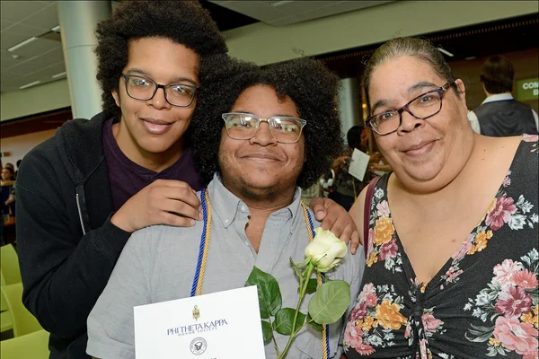 Student posing with PTK certificate and two family members