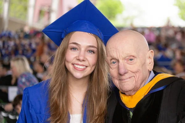 Young woman, older man smiling in commencement regalia