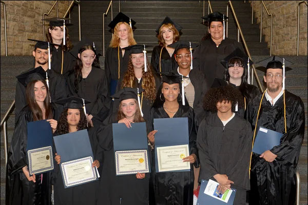 Posed photo of 15 students in black caps and gowns