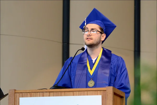 J. Naused at podium in regalia