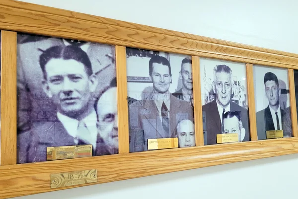 A series of black and white portraits of men on a wall