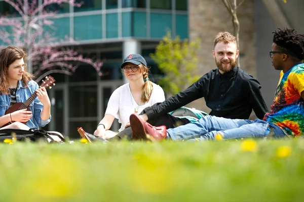 A group of students sitting in the grass outside FLCC's main campus.