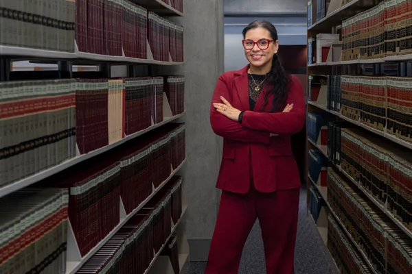 FLCC paralegal student standing in the Library among legal books.