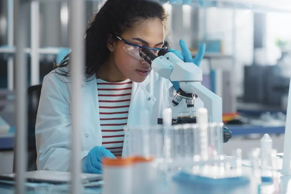 Biotech scientist uses a microscope in a laboratory.