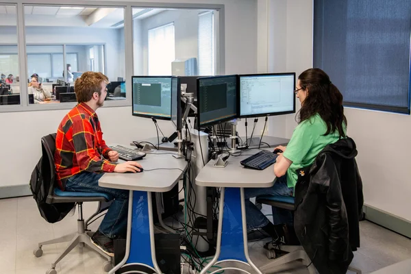 Students in computer lab using dual screen monitors.