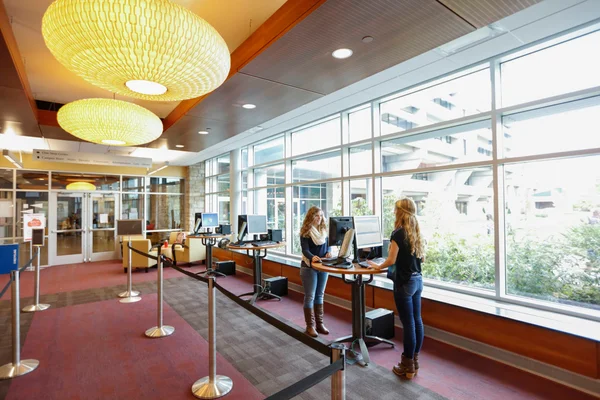 Two FLCC students standing at the One Stop Center self-service computer kiosks completing online forms.