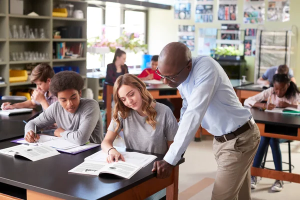 A teacher and students reviewing course materials together.