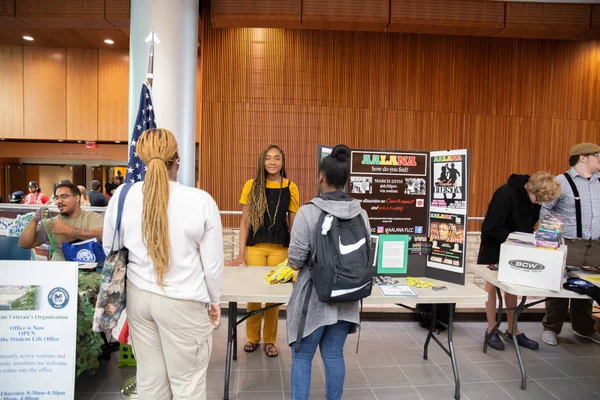 Students registering for a club during a tabling event in the FLCC main lobby.