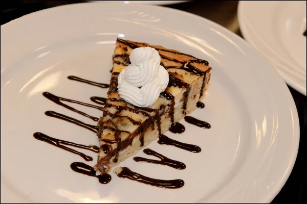 A slice of pie drizzled with chocolate and topped with a whipped cream.