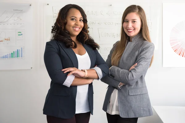 Two employees in a business setting with marketing charts and graphs displayed on the walls.