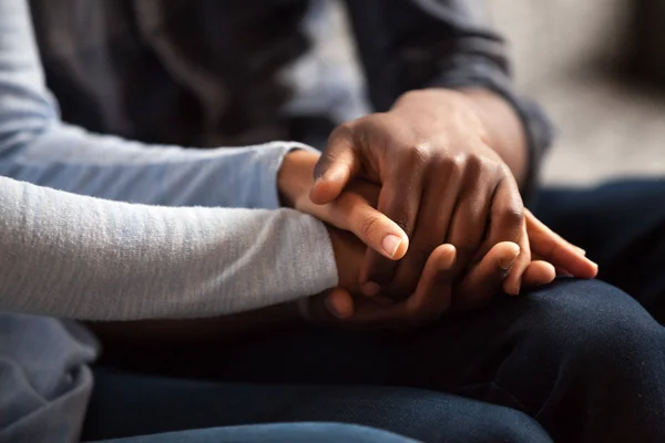 Three hands clasped together in a display of strength, support, and human connection.