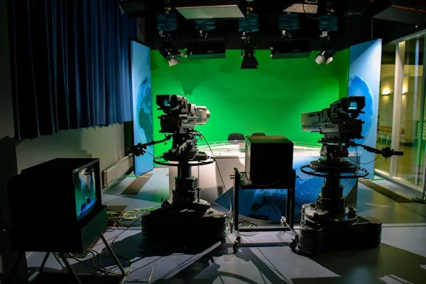 Image of empty TV studio with cameras pointing at a green screen