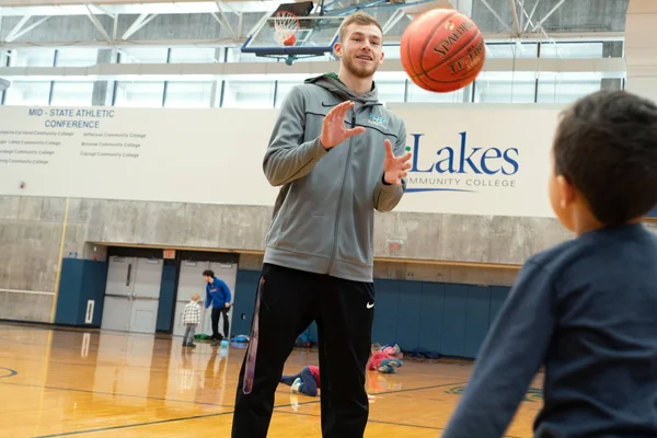 A Physical Education and Exercise Science student tossing a basketball with a grade-school student in the FLCC gymnasium