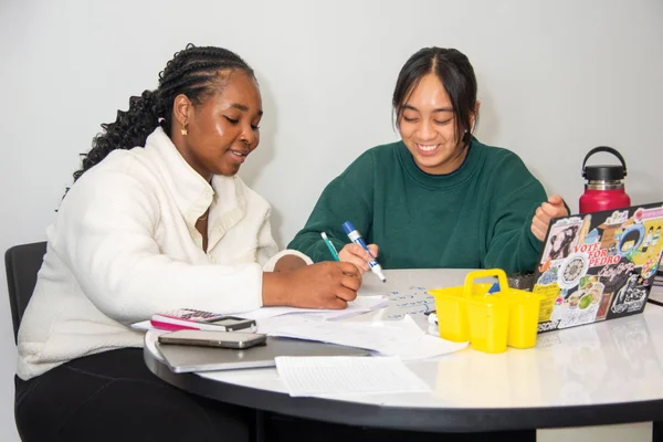 Two students work together at a whiteboard table in the Math Center to solve mathematics problems.
