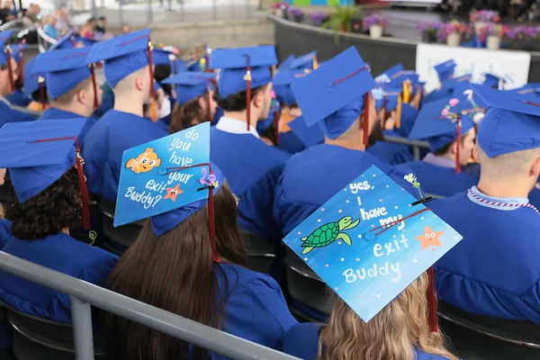 2 graduates wearing decorated mortarboards