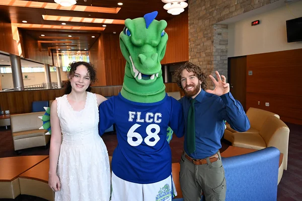A young man and woman posing on either side of the FLCC mascot