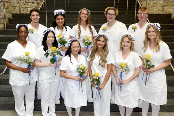 A group of 11 male and female nurses in white uniforms
