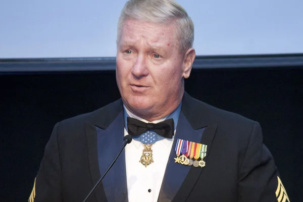 Older man at podium wearing military medals