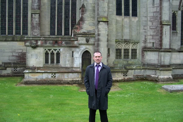 Man weariong a suit, standing in the grass