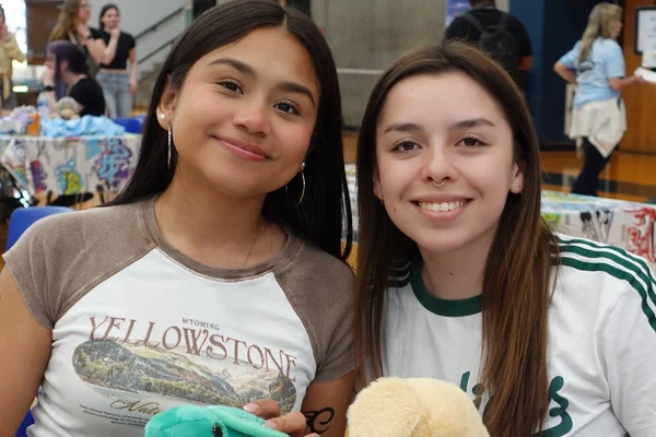 Two students sitting at a table and smiling at the camera for a posed photo