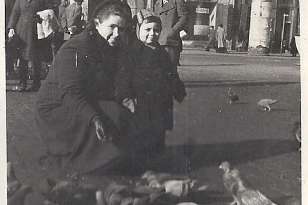 A woman bends down to feed birds with her toddler son in 1950s Wroclaw, Poland