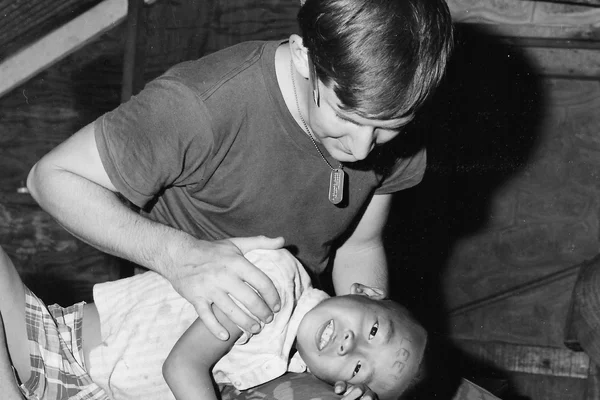 A man with his hand on a boy resting on his head on the man's lap