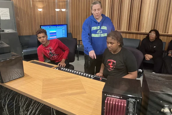 Kari Ripley, technical specialist for the music recording technology program, helps students in the Urban League of Rochester summer camp use a recording console at the main campus.