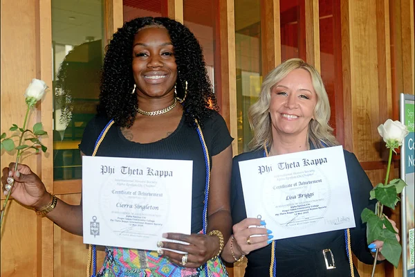 Two women holding honor society certificates