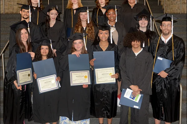 Posed photo of 15 students in black caps and gowns