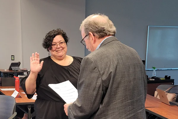 Woman raising hand to be sworn in as trustee