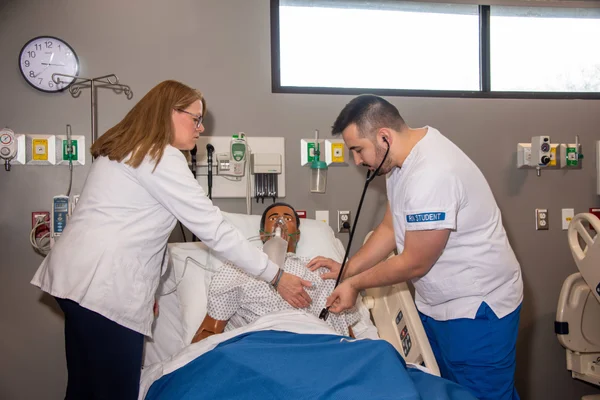 Nursing students practice assisting a patient in a simulation lab.