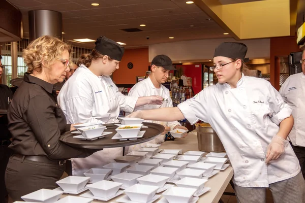 A group of Culinary Arts students in white chef's jackets dishing up soup for an event.