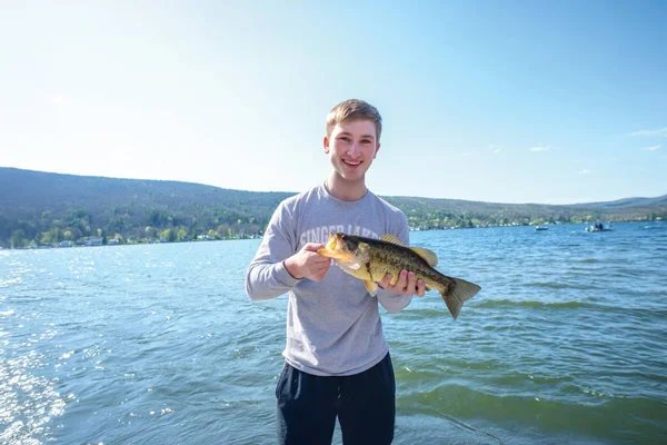 A student holding a fish captured during an FLCC field experience on Canandaigua Lake.