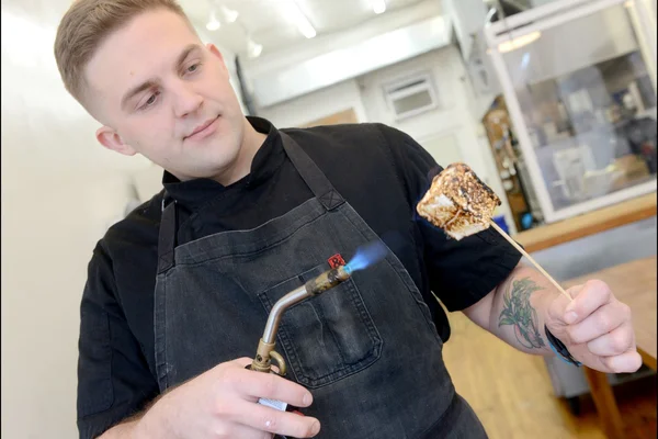 Gary Parmelee roasting a marshmellow dessert with torch