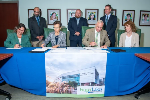 College officials at table signing documents