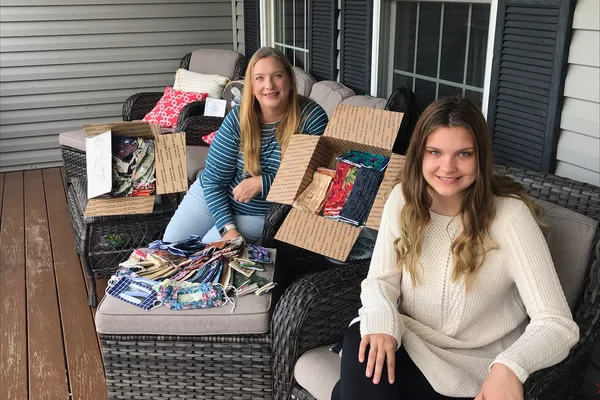 mom and daughter with face coverings on a porch