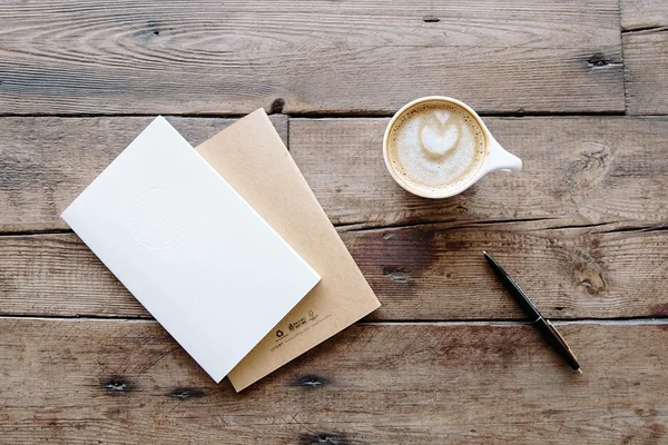 Photo of a notepad and latte on a wooden tabletop surface